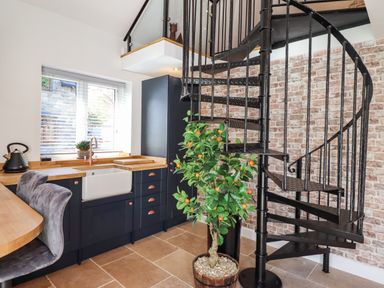 A kitchen with wooden countertops a black spiral staircase and a potted orange tree at Glyndwr in Betws-Y-Coed