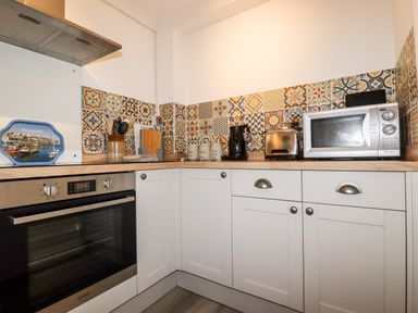 A kitchen corner with an oven microwave toaster kettle and patterned tile backsplash at EdyVean in Portmellon near Mevagissey