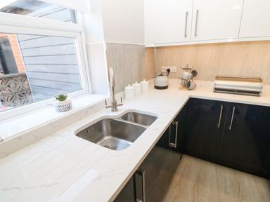 A kitchen countertop with a double sink a kettle canisters and a bread bin at Lobster Pot Retreat in Newbiggin-By-The-Sea