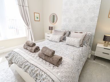 A bedroom with a double bed with towels on the bed and nightstands with lamps at Lobster Pot Retreat in Newbiggin-By-The-Sea