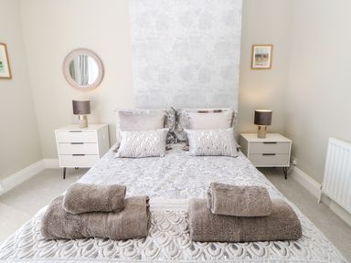 A bedroom with a double bed towels on bed and two bedside tables with lamps at Lobster Pot Retreat in Newbiggin-By-The-Sea