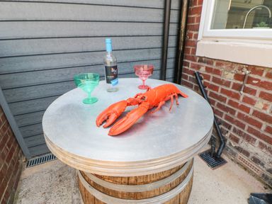 A metal table on a wooden barrel with a cooked lobster a bottle of wine and two colored glasses at Lobster Pot Retreat in Newbiggin-By-The-Sea