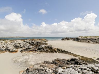A sandy beach with rocks and the ocean in the background at Ti Tom Narta in Trabane near Lettermore County Galway
