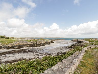 A coastal landscape with a sandy beach rocky shore and a stone wall in Trabane near Lettermore County Galway