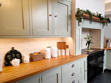 A kitchen countertop with a kettle toaster containers and flowers on a stove at Grove House in Egremont