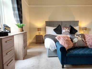 A bedroom with a bed with pillows and a blue cushioned bench at Grove House in Egremont