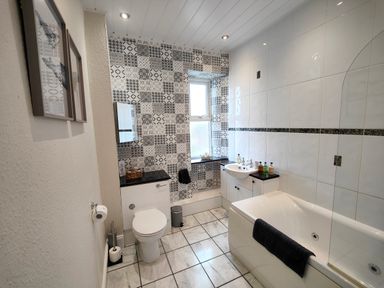 A bathroom with a toilet sink and bathtub with black and white patterned tiles at Grove House in Egremont