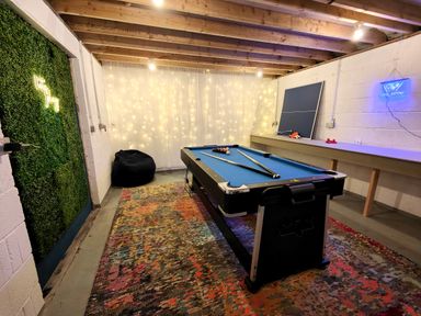 A basement game room with a pool table ping pong table and bean bag at Grove House in Egremont
