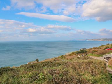 A coastal landscape with greenery overlooking the sea and a few buildings at Lodge 23 in Torpoint