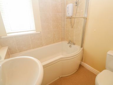 A bathroom with a bathtub shower sink window and toilet at Lodge 23 in Torpoint