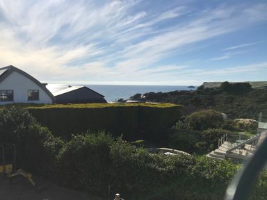A coastal view with houses trees and ocean in the distance at Lowenda in Polzeath