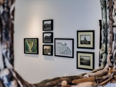 A wall with seven framed pictures including maps and photographs at Lowenda in Polzeath