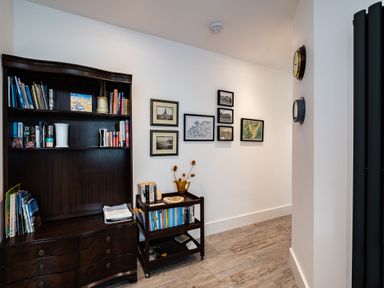 A hallway with a bookshelf and a small book cart with books and decorative items at Lowenda in Polzeath