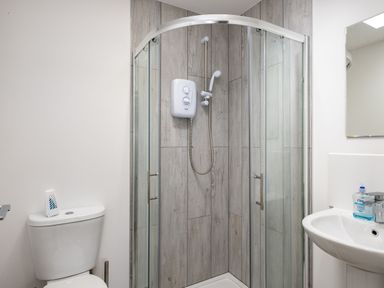 A bathroom with a corner shower enclosure a toilet and a sink with a mirror at Lowenda Polzeath