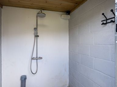 A shower area with two showerheads and a hook on a tiled wall at Lowenda in Polzeath