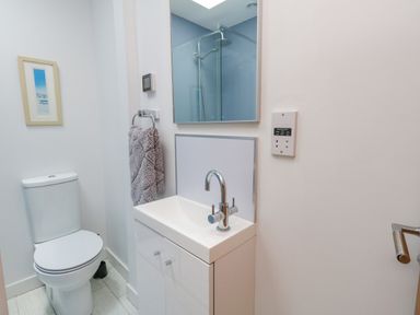 A bathroom with a toilet a sink with a faucet a mirror a towel on a rack and a framed picture on the wall at Beach Retreat in Weymouth