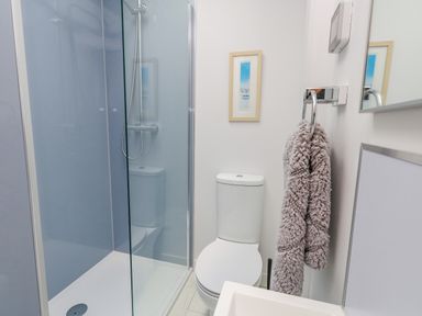 A bathroom with a shower enclosure toilet hanging towel and framed picture at Beach Retreat in Weymouth