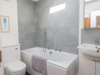 A bathroom with a bathtub towel toilet sink and mirror at Beach Retreat in Weymouth