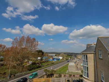 A street with cars trees and buildings under a blue sky at Beach Retreat in Weymouth