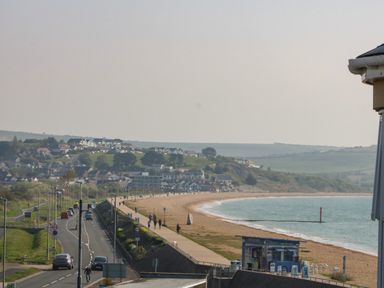 A coastal road running alongside a beach with a cafe and people walking at Beach Retreat in Weymouth