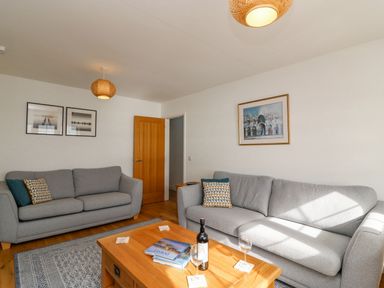 A living room with two gray sofas a wooden coffee table and framed pictures on the walls at Beach Retreat in Weymouth