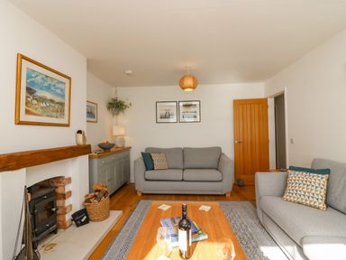 A living room with two grey sofas a wooden coffee table a fireplace and paintings on the wall at Beach Retreat in Weymouth