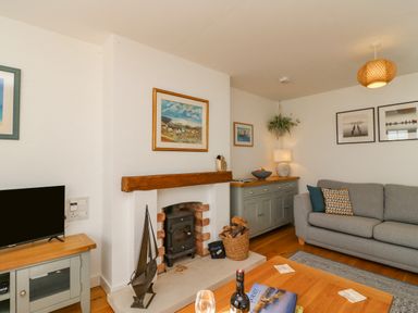 A living room with a fireplace TV grey sofa and wooden furniture at Beach Retreat in Weymouth