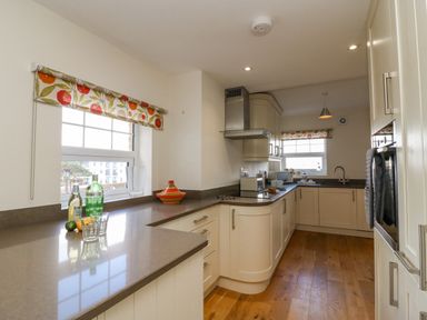 A kitchen with cream cabinets and brown countertops with windows and appliances at Beach Retreat in Weymouth