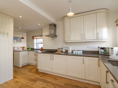 A kitchen with white cabinets a toaster kettle microwave and cups on the counter at Beach Retreat in Weymouth