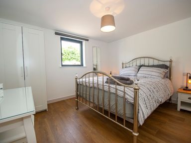 A bedroom with a metal bed frame bed bedside tables wardrobe and a window at Owl Lodge in Wedmore