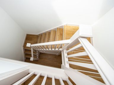 A stairway with wooden steps and white railings viewed from above at Owl Lodge in Wedmore
