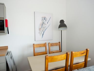 A dining area with a table and four wooden chairs a floor lamp and owl artwork on the wall at Owl Lodge in Wedmore