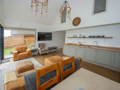 A living room and kitchen area with chairs a sofa and wooden cabinets at Owl Lodge in Wedmore
