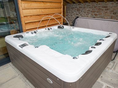 A hot tub with water jets and a wooden wall and stone wall background at Owl Lodge in Wedmore