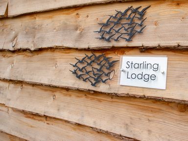 A wooden wall with two black bird decorations and a sign that says Starling Lodge at Starling Lodge in Wedmore