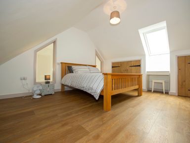 A bedroom with a wooden bed a small desk and stool wooden floor at Starling Lodge in Wedmore