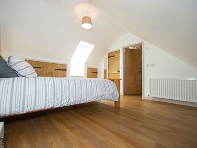 A bedroom with a wooden bed striped bedding wooden doors and a skylight window at Starling Lodge in Wedmore