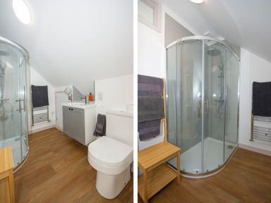 A bathroom with a curved glass shower enclosure a toilet a vanity unit with a sink wooden floor and towel racks at Starling Lodge in Wedmore