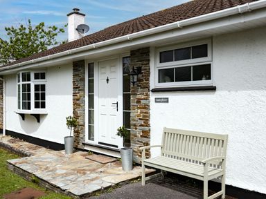 The entrance of a white house with a bench and two potted plants near the door at Samphire Rock