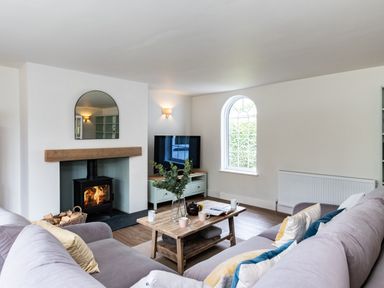A living room with a wood stove fireplace a wooden coffee table with cups a television and a sofa at Samphire in Rock