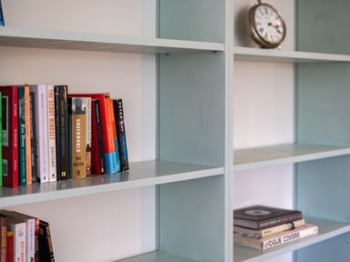 A bookshelf with books and an alarm clock on the shelves at Samphire in Rock