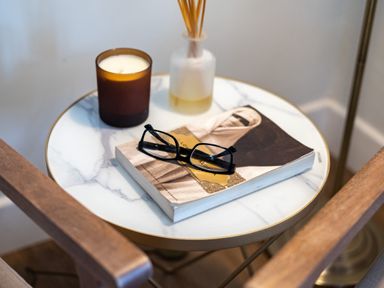 A round marble side table with a book, glasses, a candle and a diffuser at Samphire in Rock