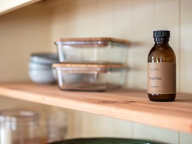 A wooden shelf with a brown bottle labeled scented oil and glass containers with wooden lids at Samphire in Rock