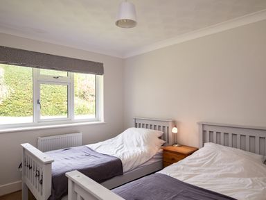 A bedroom with two single beds and a wooden nightstand with a lamp at Samphire in Rock
