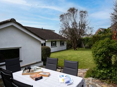 A garden with a patio table and chairs outside a white house at Samphire Rock