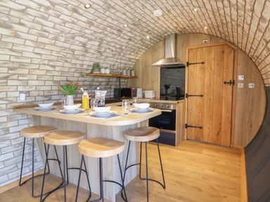 A kitchen with a wooden island and four stools under a brick vaulted ceiling at Nant y Garnedd in Mallwyd near Dinas Mawddwy