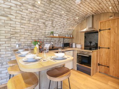 A kitchen with a wooden table set with plates bowls glasses a stove and a wooden door at Nant y Garnedd Mallwyd near Dinas Mawddwy