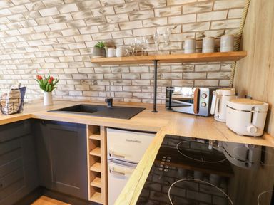 A kitchen corner with a black sink wooden countertop and shelves with dishes and jars at Nant y Garnedd Mallwyd near Dinas Mawddwy
