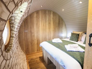 A bedroom with a bed and round window with brick wall at Nant y Garnedd Mallwyd near Dinas Mawddwy