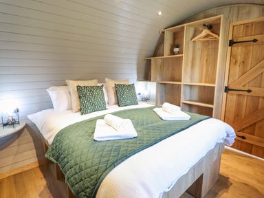A bedroom with a double bed green quilt and shelves with hangers and a door at Nant y Garnedd Mallwyd near Dinas Mawddwy